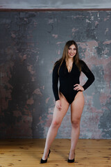 Fototapeta premium Beautiful brown-haired girl in a black bodysuit in a loft photo studio