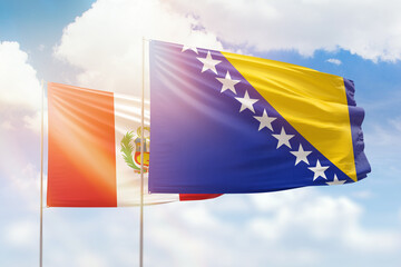 Sunny blue sky and flags of bosnia and peru