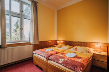 Old hotel room with two individual beds pushed together. Room has standard equipment in form of...