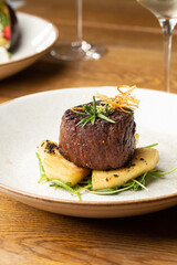 Grilled meat fillet steak medallion with green sauce, served with pear or apple. On dark background