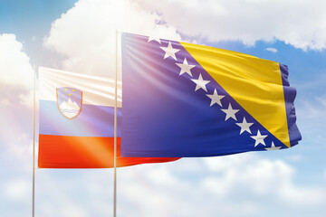 Sunny blue sky and flags of bosnia and slovenia
