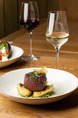 Grilled meat fillet steak medallion with green sauce, served with pear or apple. On dark background