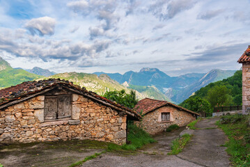 Fototapeta na wymiar Typical stone houses on top of the Asturian mountains, with a background of mountain peaks.
