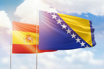 Sunny blue sky and flags of bosnia and spain