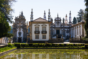Scenic view of medieval Baroque building of Mateus Palace with ornamental pond surrounded by trees...