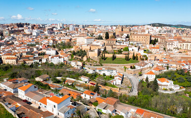 Fototapeta na wymiar Aerial view of Caceres cityscape overlooking brownish tiled roofs of historic quarter against backdrop of modern high-rise buildings in spring day, Extremadura, Spain