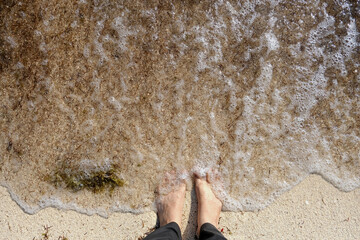 Fototapeta na wymiar Feet On Wet Sand At Beach