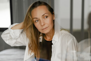 Elegant woman in  black lingerie and white blouse  sitting on bed .