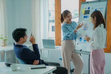 Asian and Caucasian corporate executives discuss business in a conference room of three young...