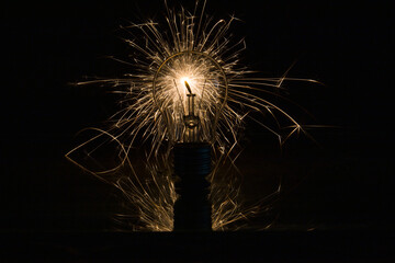 The incandescent lamp burns with sparks - obrazy, fototapety, plakaty