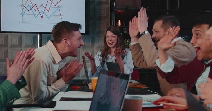 Young female CEO, company boss tells good news to team, they celebrate success giving high fives at office slow motion.