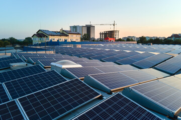 Aerial view of solar power plant with blue photovoltaic panels mounted on industrial building roof...