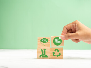 Wooden cubes with CO2 green icons over a marble floor against a green background