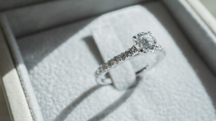 Close up of diamond ring with sunlight and shadow background. Love, valentine, relationship and wedding concept. Soft and selective focus.