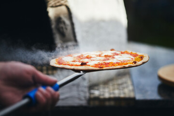 The pizza is ready and taken out of the wood-fired oven. The process of making homemade pizza. The...