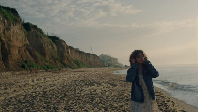 Dreamy girl walking on ocean beach. Stylish woman watching sea landscape