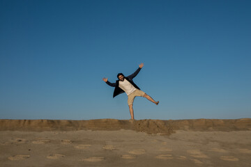 Happy single young man on beach being funny in sand with blue sky and sand
