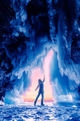 Tourist man in Ice blue cave or grotto on frozen lake Baikal. Concept beautiful adventure travel winter landscape with people - obrazy, fototapety, plakaty