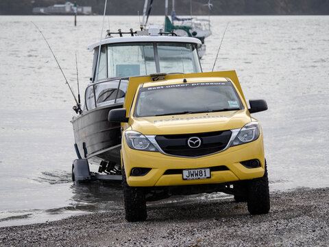 Yellow Mazda BT-50 Generation II (2011-2015) Pickup Truck Pulling Fyran Trailer Boat Out Of Water. Stock Photo.