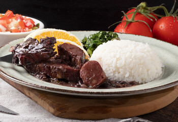 Delicious Brazilian feijoada on green plate.
