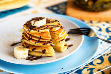 classic american breakfast. homemade banana pancakes on plate sprinkled powder and honey. A slide of hot pancakes with fresh bananas on a plate on the kitchen table . Pancake slide with honey topping