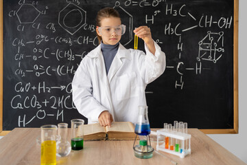 Little girl scientist examining test tube with chemical reagent. Schoolgirl making experiment in chemistry class. Research and education in school. Chemical laboratory