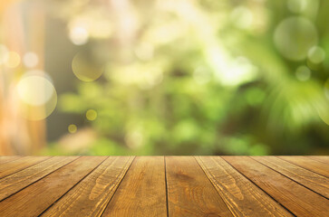 Background of green trees with blur. Brightness. In front of the picture is a wooden floor.