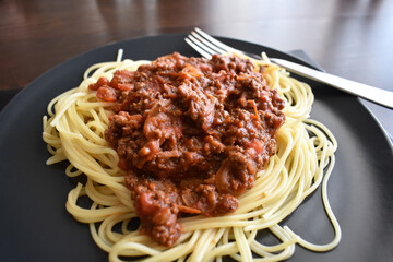Spaghetti Bolognese with minced beef, onion, chopped tomato, garlic, olive oil, stock cube, tomato puree and Italian herb. Traditional Italian food on a plate.	
