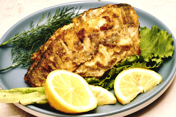 fried fish with lemon and herbs on a plate on the table