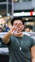 Unrecognizable person with make-up on the hand of the LBGT community, and the city in the background.	