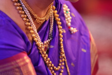 close up of a necklace with pearls on violet saree
