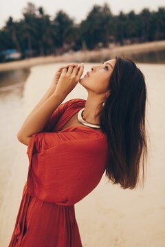 Fashion image  Of beautiful Asian woman in golden earrings and necklace posing on the beach. Soft toned image.
