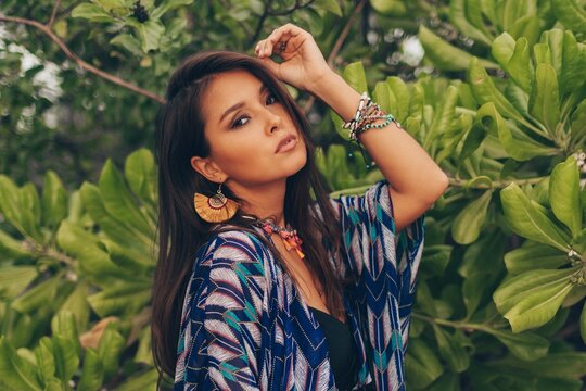 Brunette Asian woman in bohemian outfit posing in tropical garden. Freedom and travel long concept