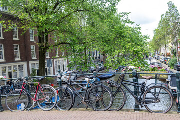 Fototapeta premium Bike on a bridge over canal, boat on water. Traditional house brick facade. Amsterdam, Netherlands.