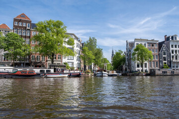 Houseboat and boat in canal, Amsterdam. Traditional house, residential neighborhood, Netherlands