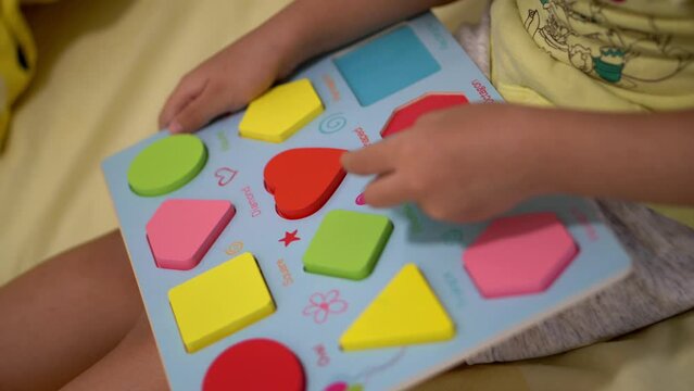 An Asian kid play the colorful shape sorting toy