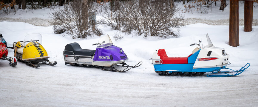 NISSWA, MN - 21 JAN 2022: Old McCulloch, Viking and Polaris Charger snowmobiles sit on a snow covered parking lot in winter. 1960s and1970s vintage sleds.
