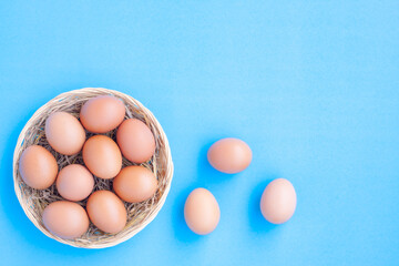 Chicken Eggs in a basket on blue with grain background