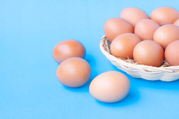 Chicken Eggs in a basket on blue with grain background