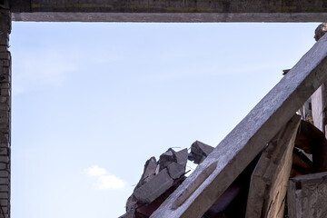 A break in the wall of a building with a pile of large concrete fragments against a background of clear sky. Background