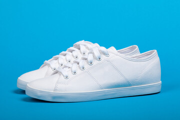 Pair of new white sneakers on blue background