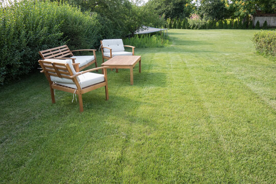 Table and chairs standing on a lawn at the garden, backyard. Outdoor garden furniture.