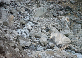 Natural landscape of rocky cascade stream among green valley and big stone