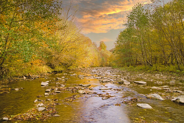 View of the river idyllic landscape when the sun is about to set over the hill on a colorful autumn day.