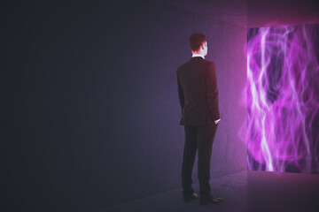 Back view of young businessman standing in abstract interior with bright glowing tech wave window view and mock up place on gray wall. Innovation, metaverse and cyberspace concept.