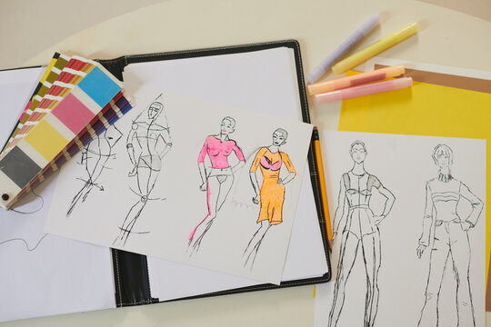 Fashion sketches, color palette and felt tip pens on desk of fashion designer