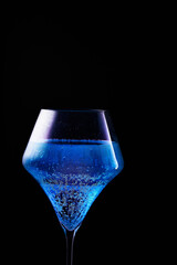 Blue drink is poured into a glass. Black background.