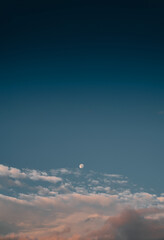 Moon in the sunset sky with clouds. Concept of peaceful and tranquil evening.