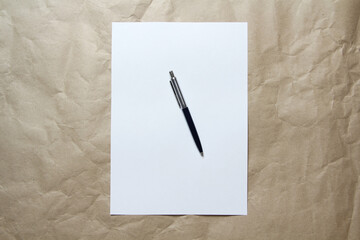 White empty sheet of A4 format with pen on a beige craft paper. Concept of analysis, study, attentive work. Stock photo with empty place for your text and design.