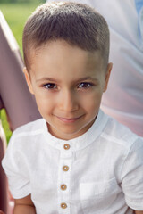 portrait of a four-year-old boy in a white shirt on a field in summer